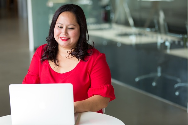 A female professional researching knowledge management tools on a laptop, actively evaluating the best options for her organization